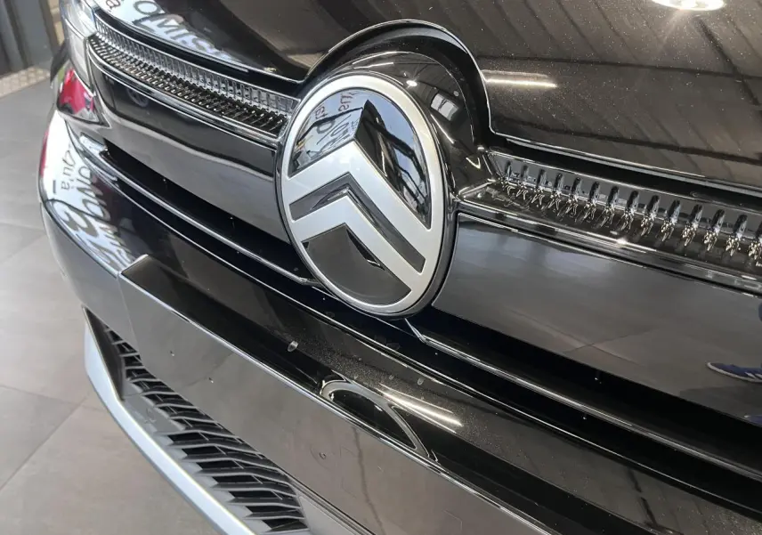 Gros plan sur la calandre avant noire métallisée de la Citroën C4 2025 avec logo chromé distinctif.