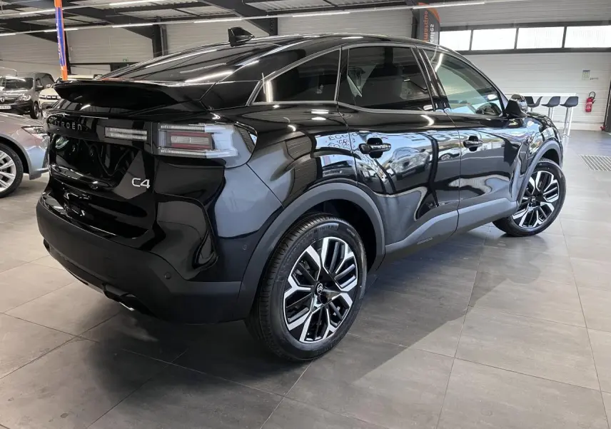 Vue 3/4 arrière droite d'une Citroën C4 noire métallisée avec jantes alliage 18'' et feux arrière LED en showroom.
