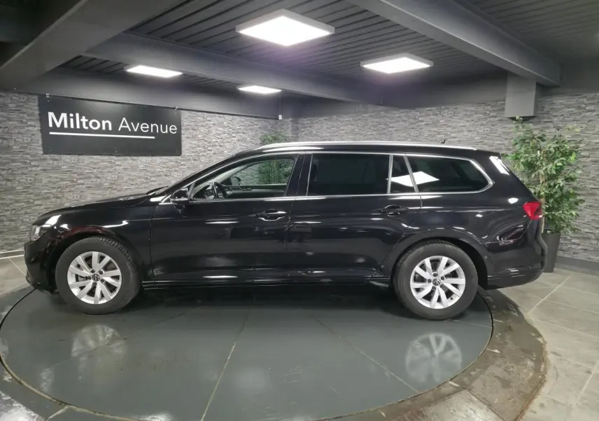 Vue latérale droite d'une Volkswagen Passat SW noire avec vitres arrière surteintées dans un showroom.