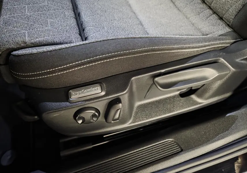 Gros plan sur la commande de réglage du siège avant tissu noir avec surpiqûres blanches de la Volkswagen Passat SW 2023.