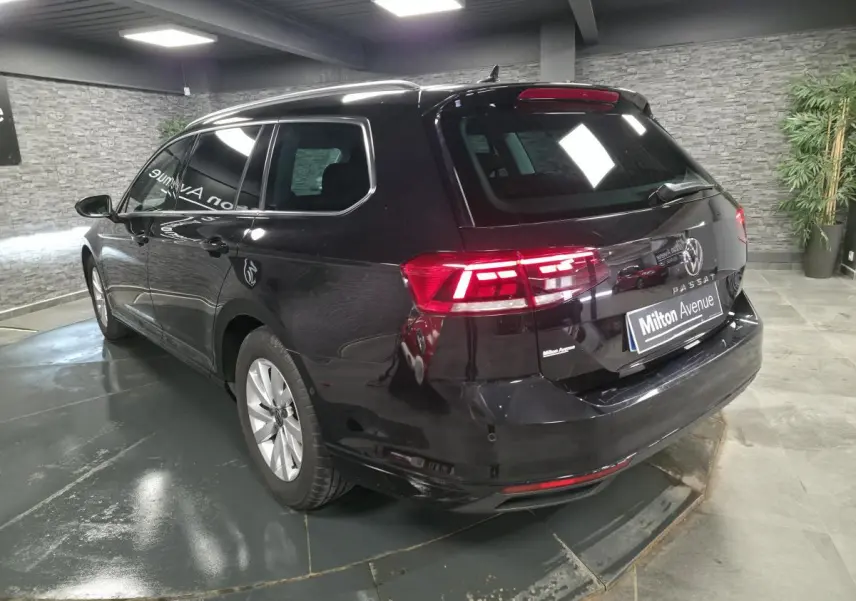 Volkswagen Passat SW noire vue 3/4 arrière droit avec vitres arrière surteintées en intérieur showroom.