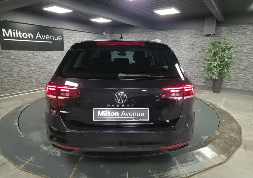 Vue arrière d'une Volkswagen Passat SW noire avec feux LED allumés dans un showroom intérieur.