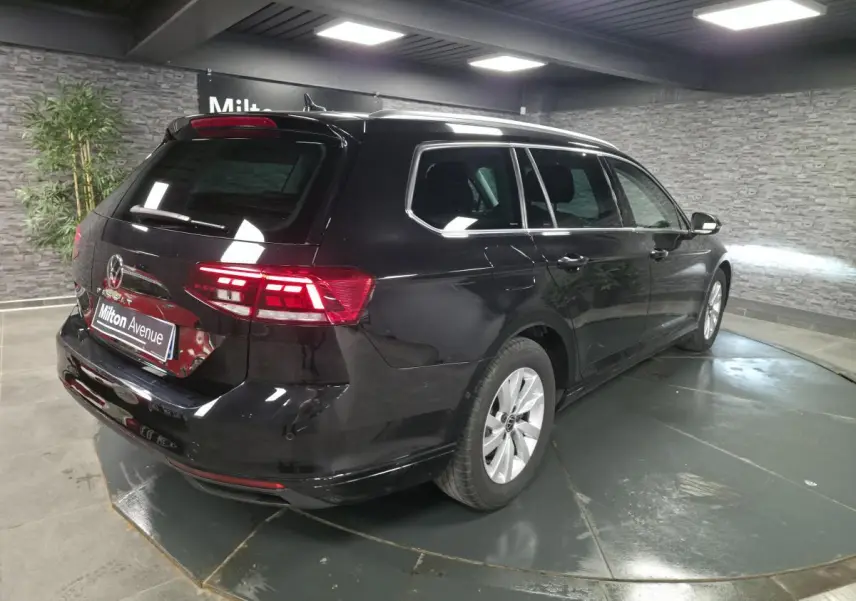 Volkswagen Passat SW noire vue 3/4 arrière droit en intérieur avec vitres arrière surteintées.