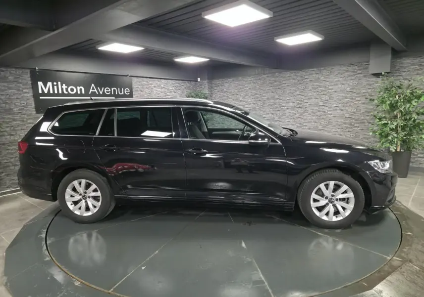 Volkswagen Passat SW noire vue de profil côté gauche en intérieur avec jantes alliage argentées.