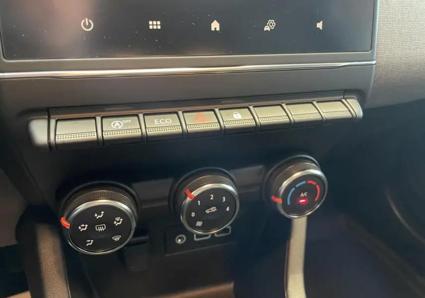 Gros plan sur les commandes de climatisation et boutons fonctionnels du tableau de bord de la Renault Clio gris Rafale.