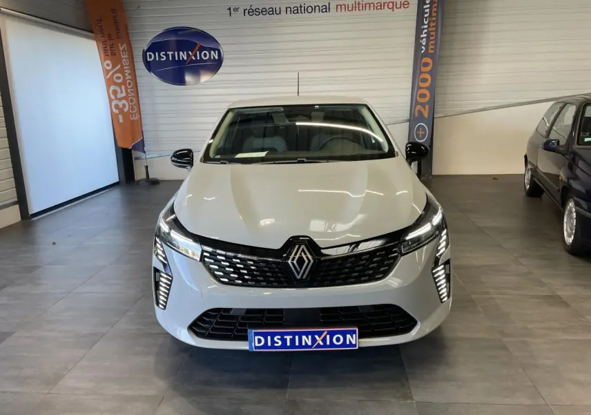Vue avant d'une Renault Clio 2025 gris Rafale avec calandre noire et feux LED allumés en showroom.