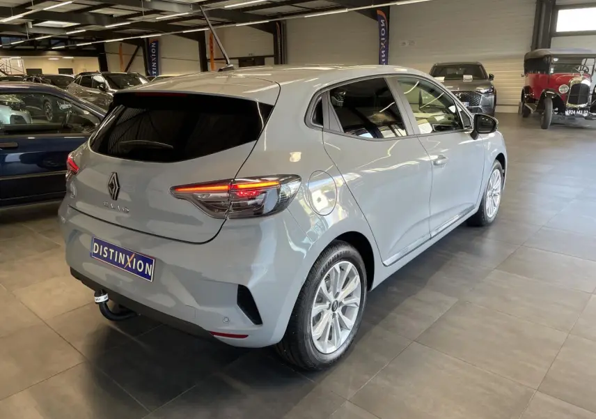 Renault Clio 1.5 Blue dCi gris Rafale vue 3/4 arrière droit en intérieur avec feux arrière LED allumés.