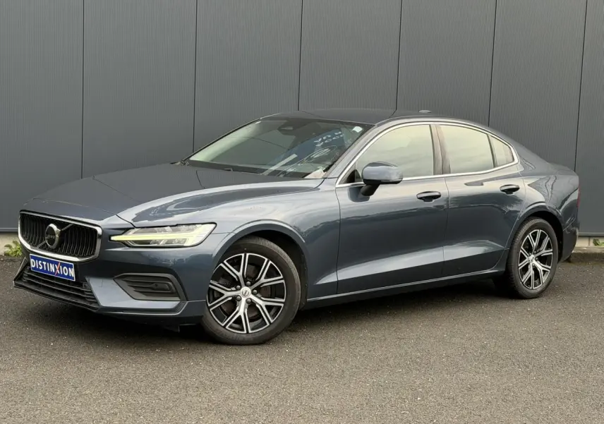 Volvo S60 gris Denim vue 3/4 avant droit, avec jantes alliage 17 pouces et contours de fenêtres chromés.