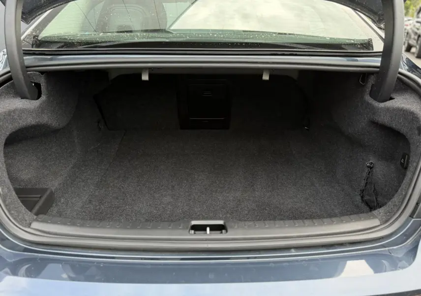 Coffre ouvert vu de l'arrière d'une Volvo S60 2024 gris Denim, montrant un espace de rangement vide et propre.