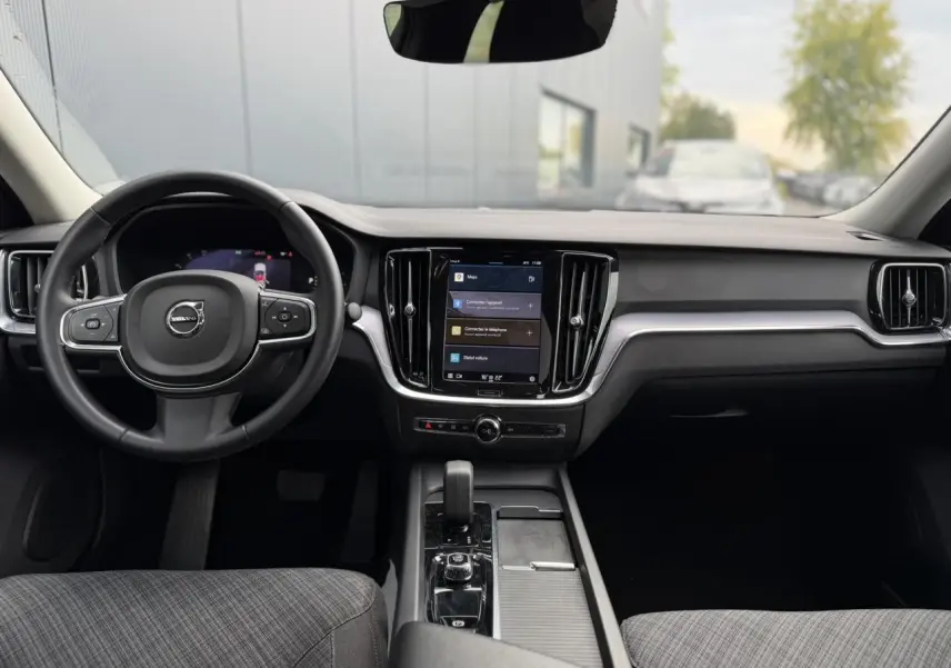 Vue intérieure avant du Volvo S60 gris Denim 2024, avec tableau de bord moderne et écran tactile central.