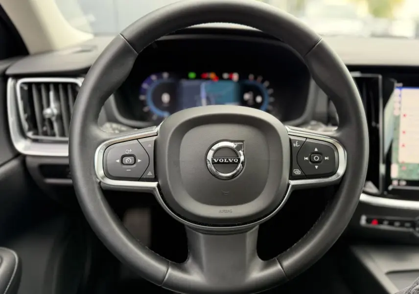 Volant noir de Volvo S60 2024 en vue frontale avec tableau de bord digital et écran tactile visible.