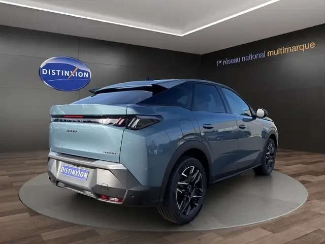 Vue 3/4 arrière droite d'un Peugeot 3008 hybride bleu avec jantes 19 pouces dans un showroom moderne.