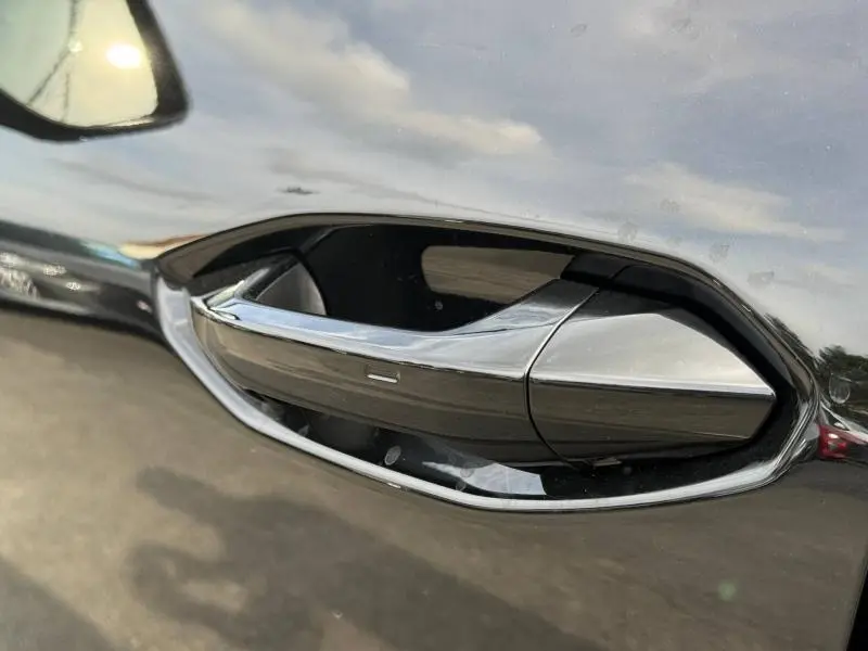 Gros plan sur la poignée de porte chromée du côté gauche d’un Audi Q3 2026 Noir Mythique métallisé.