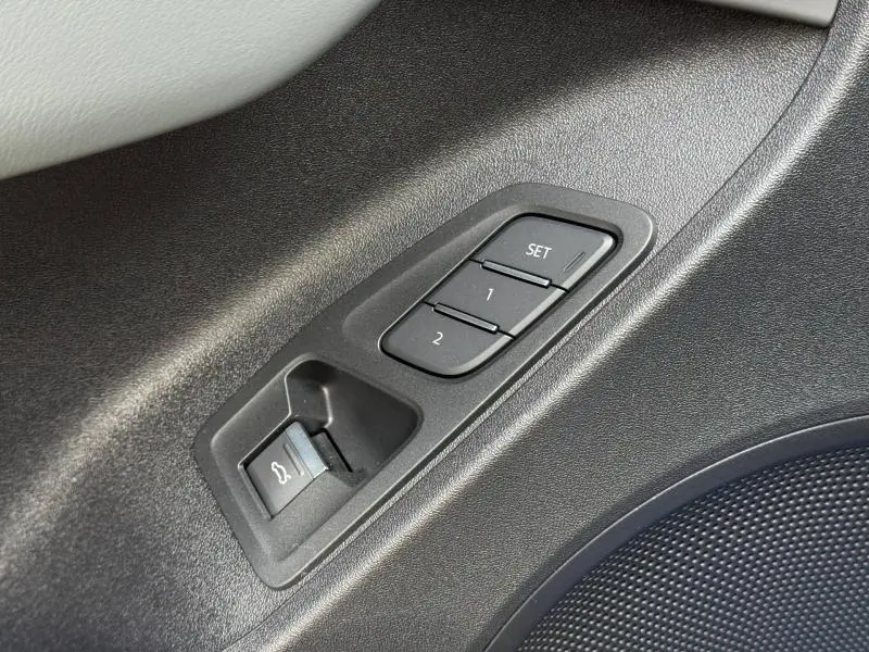 Détail des commandes de réglage mémoire des sièges et ouverture du coffre sur la porte intérieure d’un Audi Q3 noir Mythique métallisé.