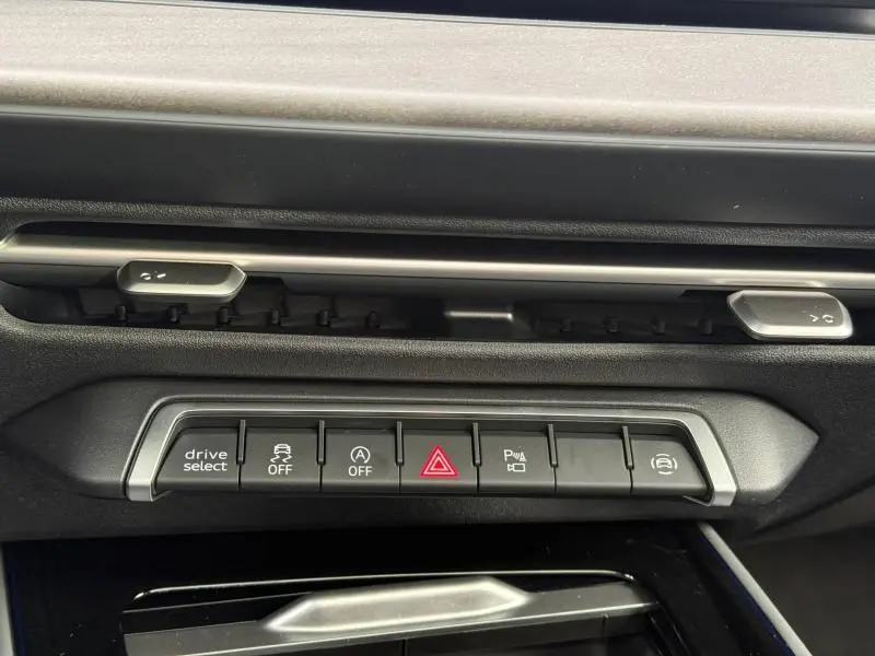 Gros plan sur la rangée de boutons de commande du tableau de bord de l'Audi Q3 2026, finition S line, intérieur noir.