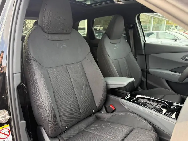 Vue intérieure sur les sièges avant noirs S line du Audi Q3 2026, avec console centrale et toit ouvrant visibles.