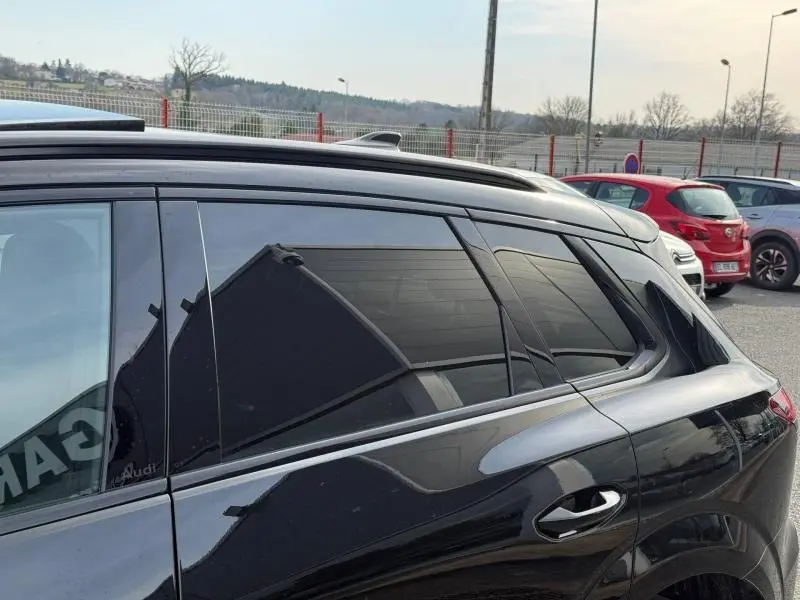 Vue latérale côté gauche d'un Audi Q3 2026 noir mythique métallisé avec vitres teintées et toit ouvrant.
