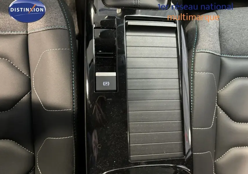 Gros plan sur la console centrale noire et les sièges en tissu gris avec surpiqûres blanches de la Citroën C4 blanche 2022.