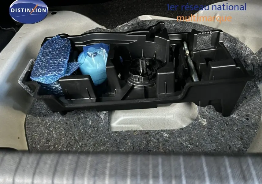 Coffret d'outils et accessoires dans le coffre d'une Citroën C4 blanche, vue plongeante sur le rangement arrière.