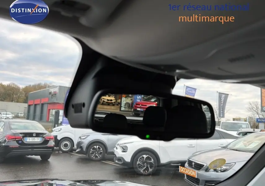 Vue depuis l'intérieur montrant le rétroviseur central avec reflet d'un Jeep Renegade noir en 3/4 arrière.