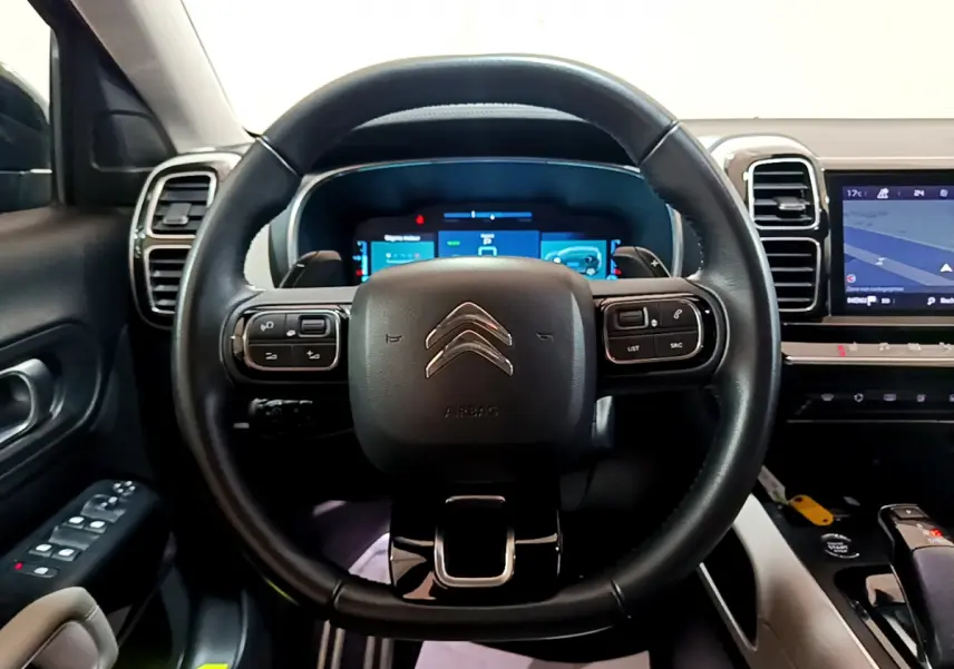 Vue intérieure centrée sur le volant cuir noir et le tableau de bord numérique du Citroën C5 Aircross Hybrid 225 ë-EAT8 Shine.