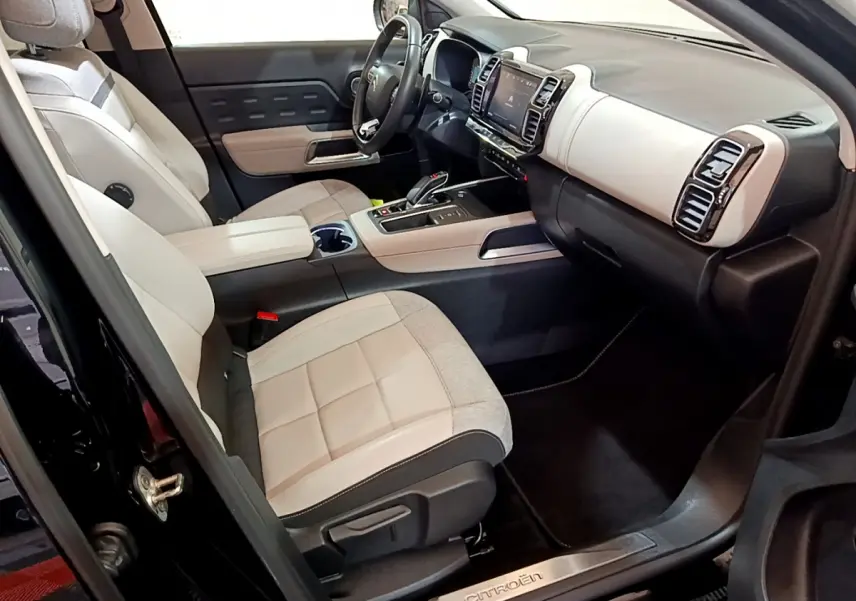 Intérieur avant droit du Citroën C5 Aircross Hybrid noir, sièges clairs et tableau de bord moderne avec écran tactile.
