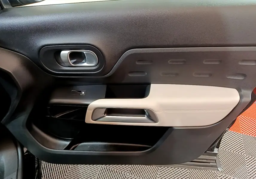 Vue intérieure côté gauche de la porte avant du Citroën C5 Aircross Hybrid 225 ë-EAT8 Shine avec garniture noire et beige.