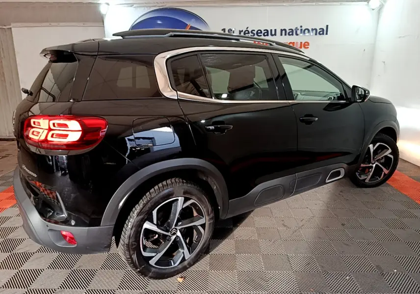 Vue 3/4 arrière droite d'un Citroën C5 Aircross Hybrid 225 noir avec feux arrière LED et jantes alliage bicolores.