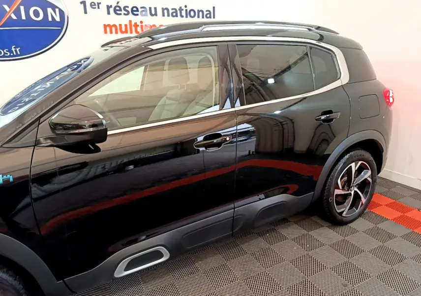 Profil côté gauche du Citroën C5 Aircross Hybrid noir 2021 avec jantes distinctives et protections de bas de caisse grises.
