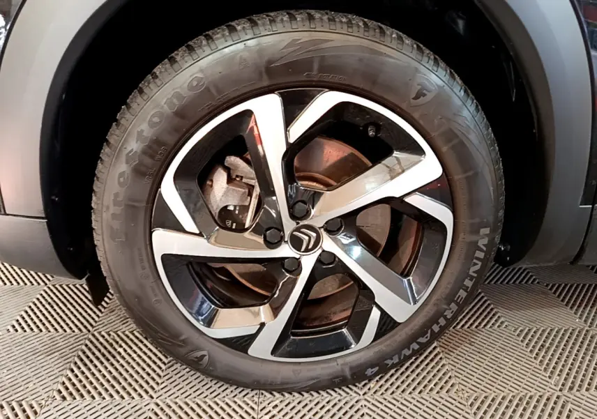 Gros plan sur la jante noire et argentée du côté avant gauche du Citroën C5 Aircross Hybrid 225 ë-EAT8 Shine noir.