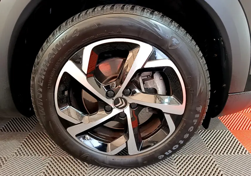Gros plan sur la roue avant gauche noire du Citroën C5 Aircross Hybrid 225 ë-EAT8 Shine avec jante alliage bicolore.