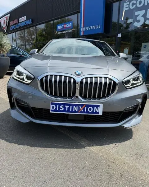 Vue frontale d’une BMW Série 1 118d gris foncé avec calandre imposante et phares LED distinctifs.