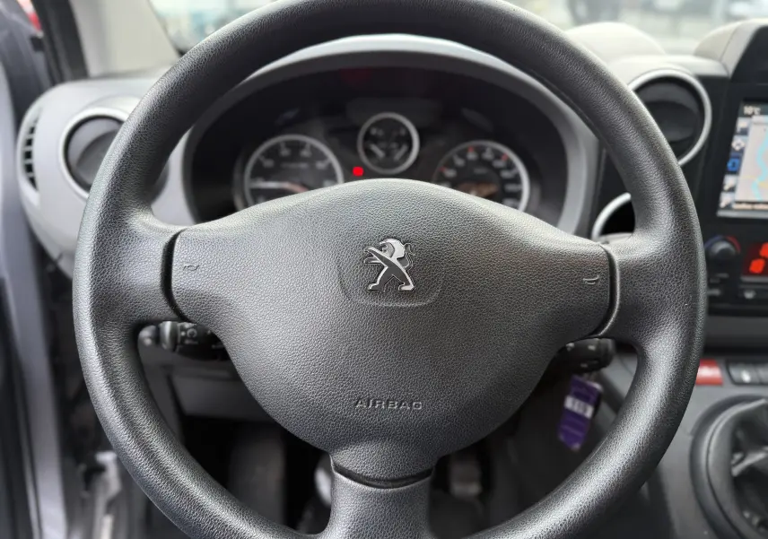 Vue rapprochée du volant noir de la Peugeot Partner Tepee 2018 avec tableau de bord et écran GPS partiellement visibles.