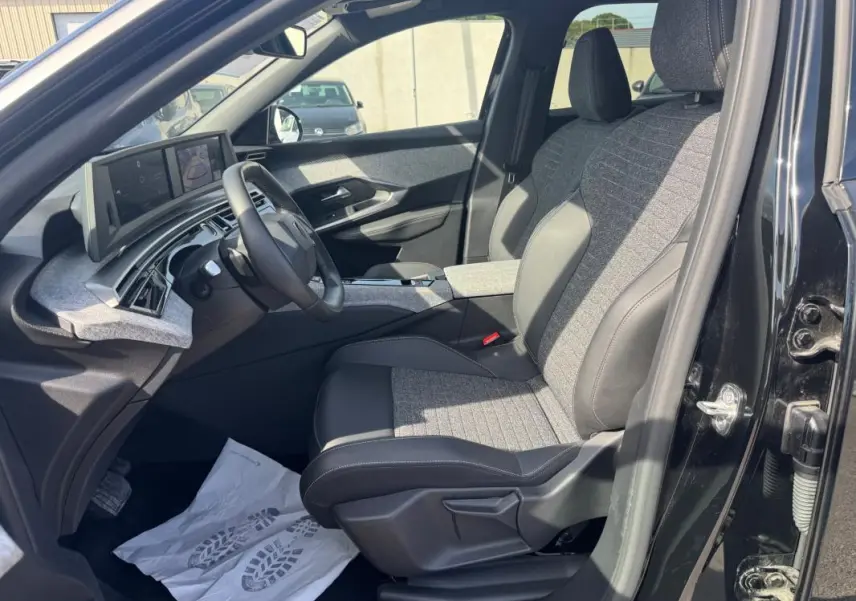 Vue intérieure côté conducteur du Peugeot 3008 Hybrid 145 Allure 2025 noir, avec sièges tissu et cuir et cockpit numérique.