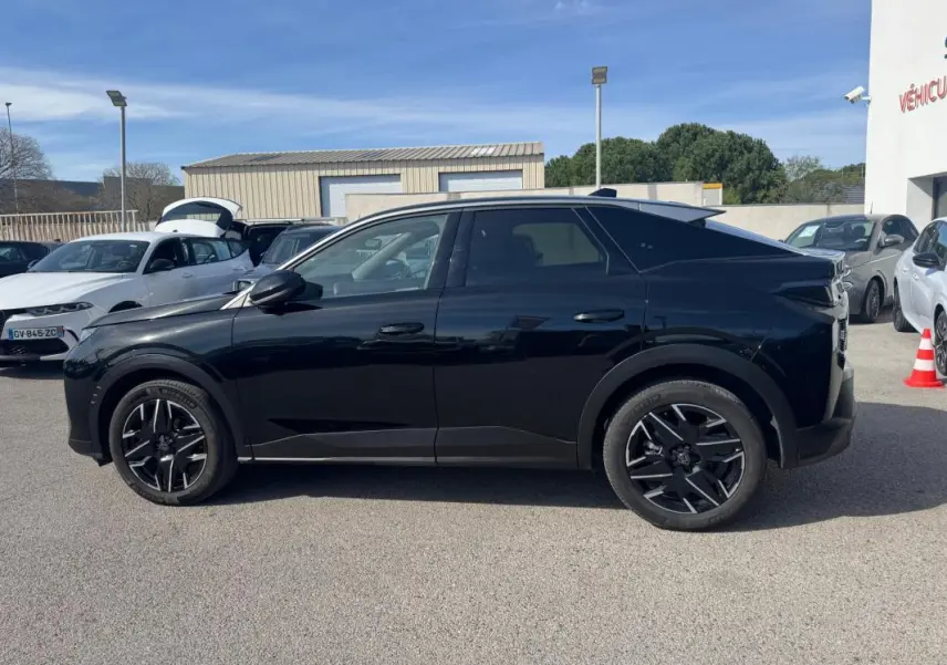 Vue latérale droite d’un Peugeot 3008 Hybrid 145 noir avec jantes alliage noires de 19 pouces sur parking extérieur.