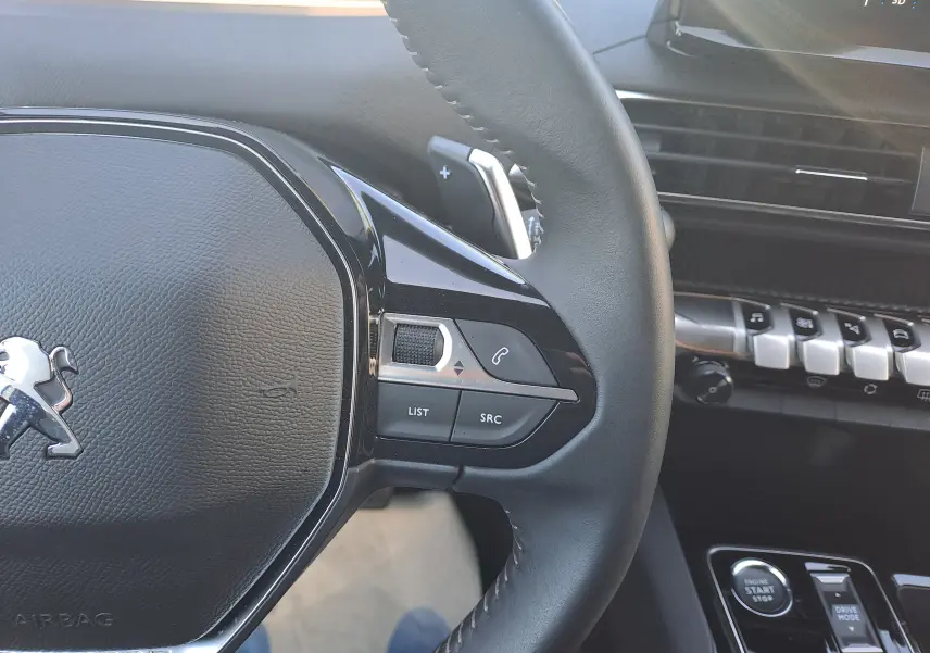 Gros plan sur le volant noir du Peugeot 3008 2023 avec commandes intégrées et partie de la console centrale visible.