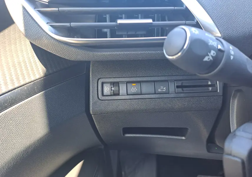 Détail intérieur côté gauche du tableau de bord du Peugeot 3008 2023, avec commandes d'assistance et aérateur noir.