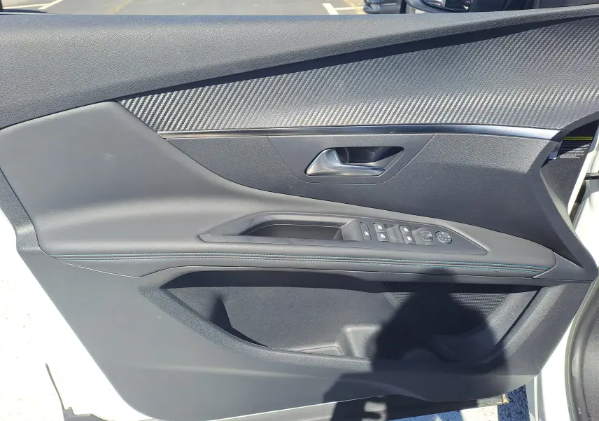 Vue rapprochée de la porte avant gauche du Peugeot 3008 blanc nacré avec garniture noire et surpiqûres bleues.