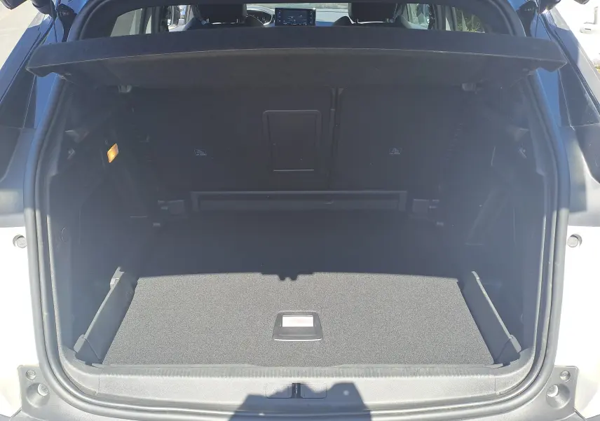 Coffre ouvert vu de l'arrière d'un Peugeot 3008 blanc nacré avec toit noir, intérieur de coffre noir spacieux et propre.