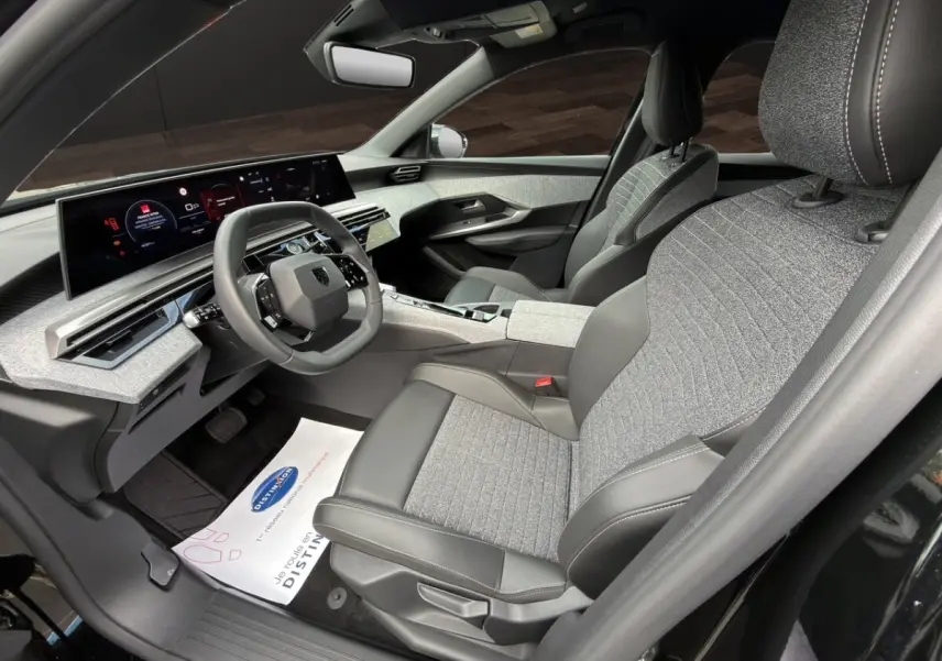 Vue intérieure côté conducteur du Peugeot 3008 noir 2026, sièges tissu et cuir, tableau de bord numérique panoramique.