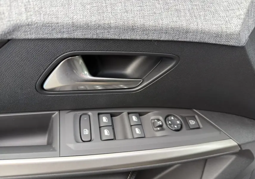 Gros plan sur la poignée intérieure et les commandes de vitres côté conducteur d’un Peugeot 3008 noir, finition Allure.