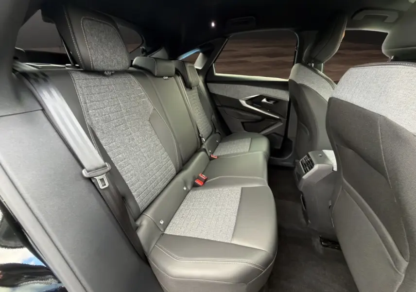 Vue intérieure arrière côté droit du Peugeot 3008 2026 hybride noir, sièges tissu et cuir gris avec ceintures de sécurité.