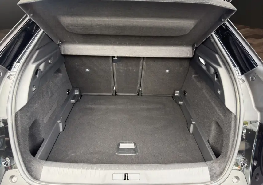 Coffre ouvert noir du Peugeot 3008 1.2 Hybrid 145 vue arrière, montrant l'espace de chargement et la tablette cache-bagages.