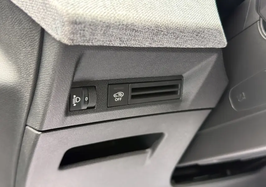 Détail intérieur côté gauche du tableau de bord noir du Peugeot 3008 1.2 Hybrid avec commande réglage phares et bouton off.