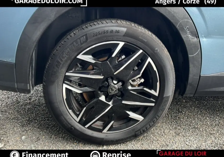 Gros plan sur la roue avant droite d’un Peugeot 5008 bleu 2024 avec jante alliage noire et argentée.