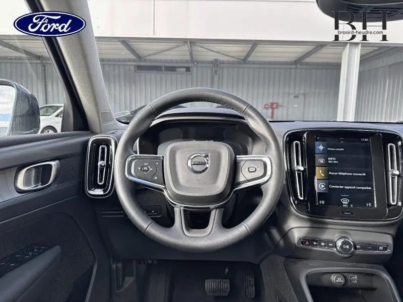 Vue intérieure frontale du volant et tableau de bord du Volvo XC40 T4 Recharge en cuir anthracite avec écran tactile central.