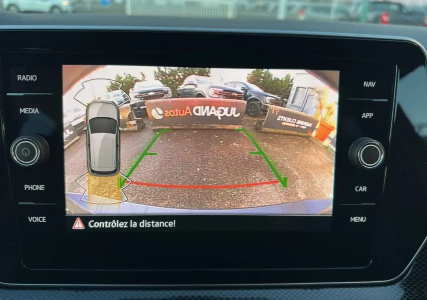 Vue écran caméra de recul du Volkswagen T-Cross gris cendré avec guidage de trajectoire et alertes de proximité.