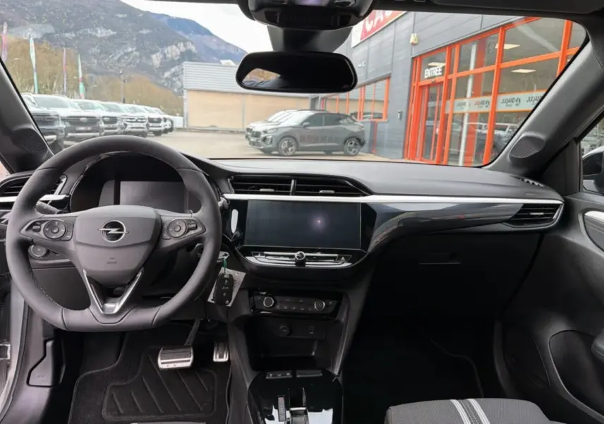 Intérieur de l’Opel Corsa Hybrid 110 e-DCT6 gris kristall, vue du poste de conduite avec volant multifonctions et écran tactile central.