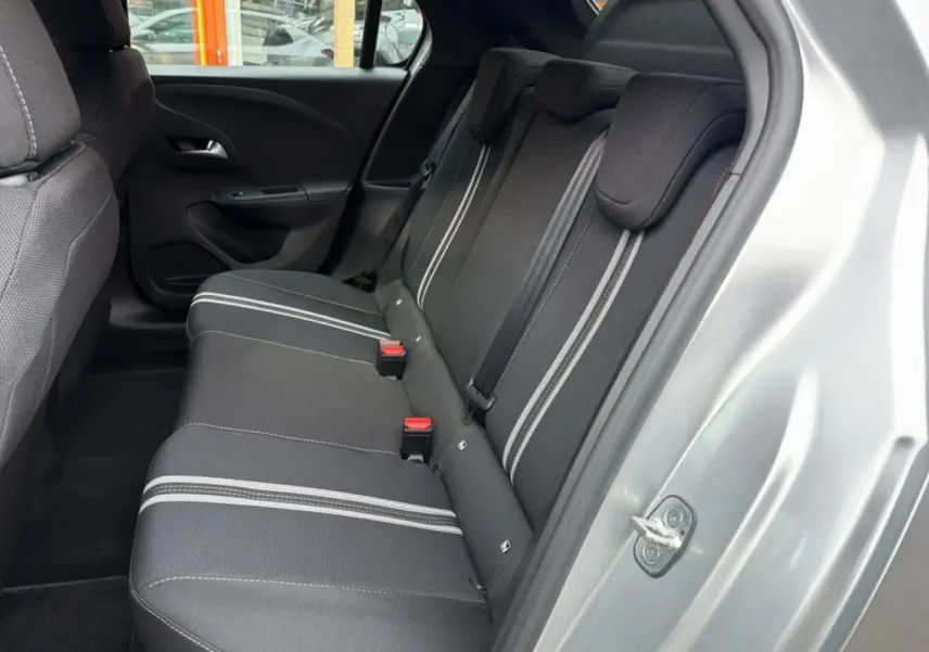 Vue intérieure arrière côté droit de l’Opel Corsa gris kristall, banquette tissu noire avec bandes grises et ceintures rouges.