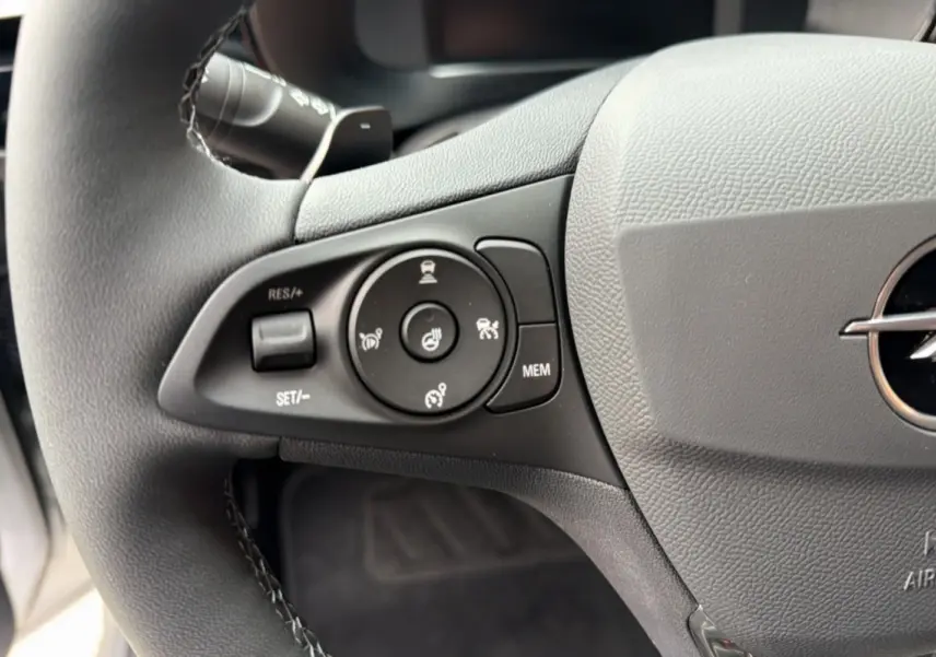 Gros plan sur le volant cuir gris de l’Opel Corsa Hybrid 2026, avec commandes multifonctions et logo Opel visible.